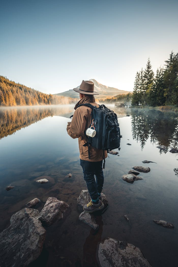 A hiker with a backpack stands by a tranquil mountain lake, capturing the essence of adventure and serenity.